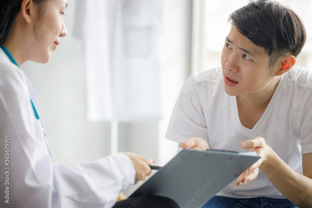 Beautiful young Asian female doctor is recording a medical history on the clipboard and explaining something to the male patient. Medical and health care concepts Beautiful young Asian female doctor is recording a medical history on the clipboard and explaining something to the male patient. Medical and health care concepts