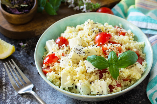 Oriental cuisine. Healthy salad with couscous, tomatoes, feta cheese, basil, chili pepper and olive oil.
