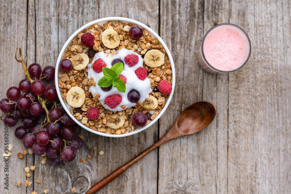Oatmeal with raspberries, grapes, banana and a glass of yogurt on a wooden background. Breakfast porridge with berries. Oatmeal with raspberries, grapes, banana and a glass of yogurt on a wooden background. Breakfast porridge with berries.