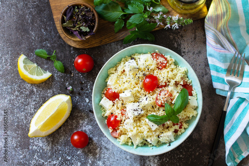 Oriental cuisine. Healthy salad with couscous, tomatoes, feta cheese, basil, chili pepper and olive oil. Top view flat lay background.