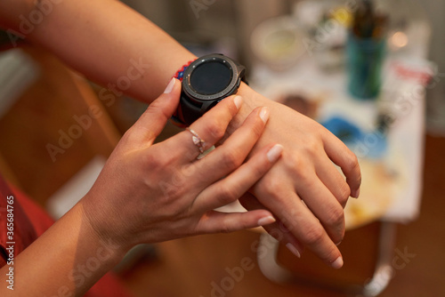 Top view of female hands setting smart watch. Close up of woman hands using smartwatch. Dramatic ambient light  golden hour.