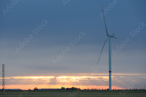 Beautiful view of field with wind turbine at sunset. Alternative energy source