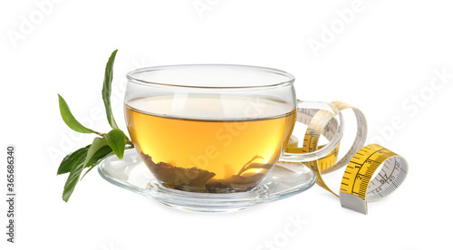 Glass cup of diet herbal tea, green leaves and measuring tape on white background