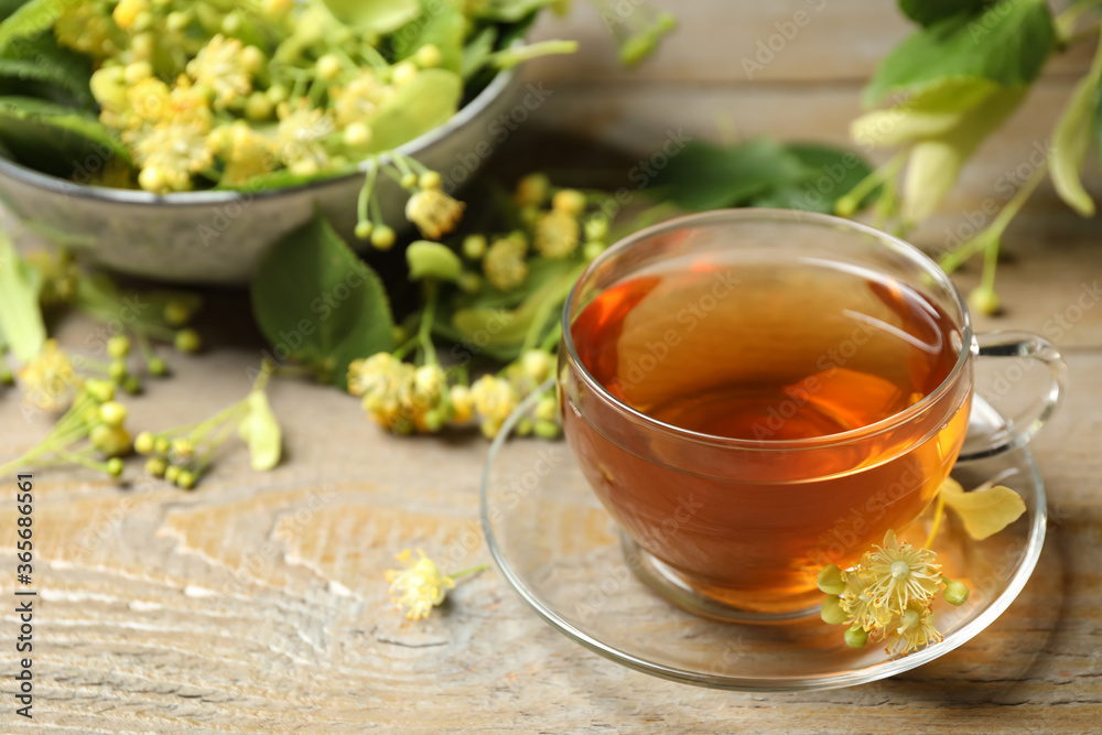 Cup of tea and linden blossom on wooden table. Space for text Cup of tea and linden blossom on wooden table. Space for text