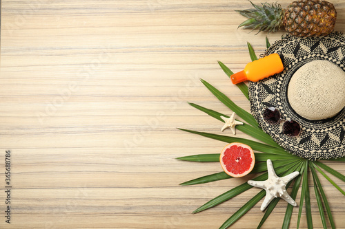Flat lay composition with fruits and beach objects on wooden background. Space for text