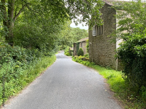 Country lane  with old houses  trees and a bridge near  Ilkley  UK