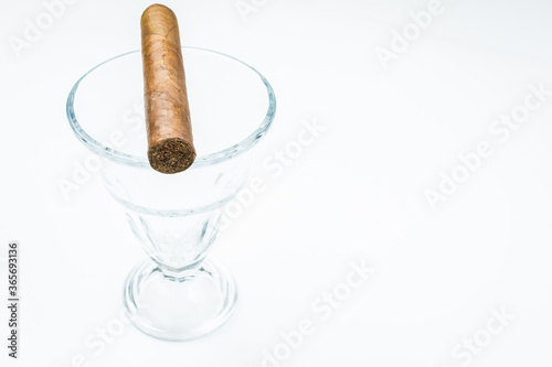 Thick cigar from twisted sheets in glass bowl with white background.