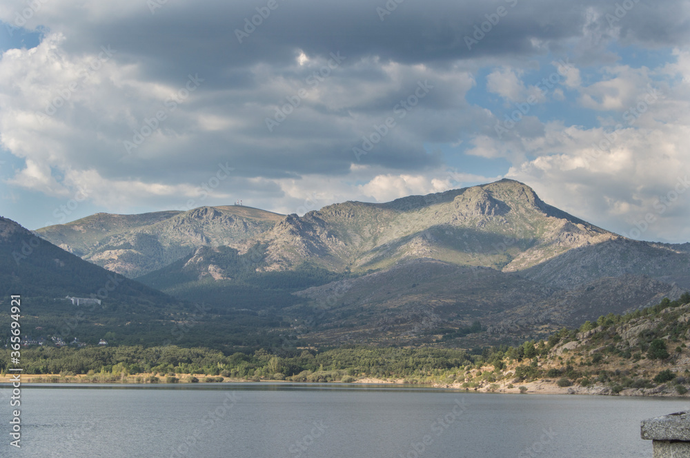 Navacerrada reservoir with the Ball of the World and the Maliciosa in the background and sky with clouds at 