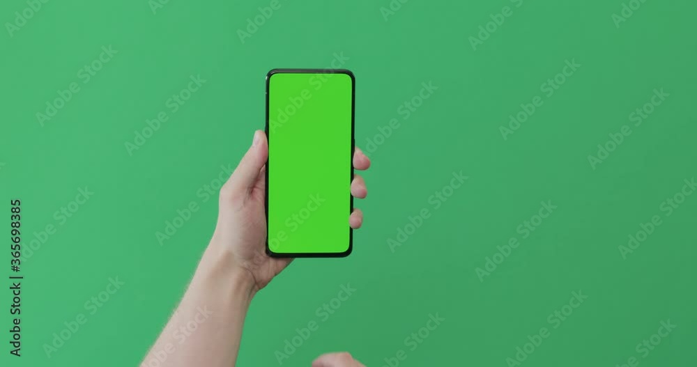 Young man hand use smartphone with green screen on green background