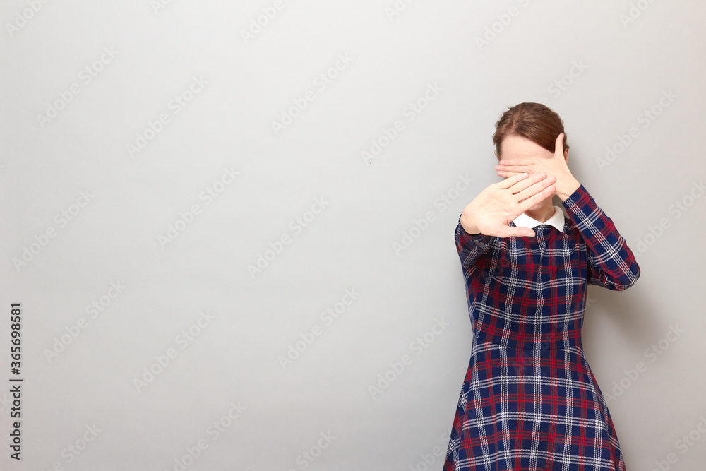 Shot of disgruntled girl covering her face, stretching palm to camera Shot of disgruntled girl covering her face, stretching palm to camera