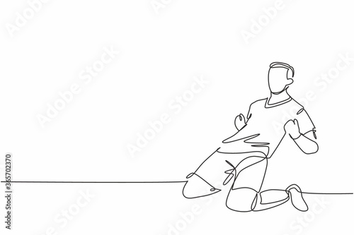 One continuous line drawing of young sporty soccer player sliding on the field emotionally after scoring a goal. Match goal scoring celebration concept single line draw design vector illustration