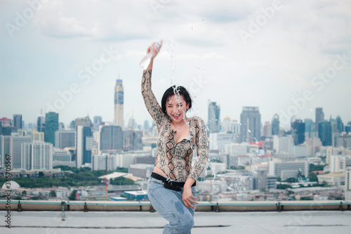 Asian attractive sexy dancer women dancing during pour water form the bottle on rooftop with skyscraper city view, hip hop street dance