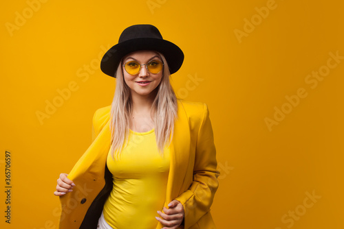 Stylish trending young woman in bright clothes on yellow background, copy space. Cool blonde