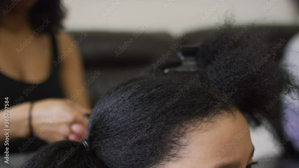 Young girl having her hair parted into sections before having it blow-dried and straightened