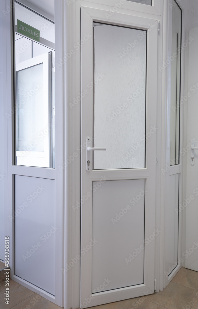 White pvc doors and a green sign with the inscription Exit. White pvc doors and a green sign with the inscription Exit.