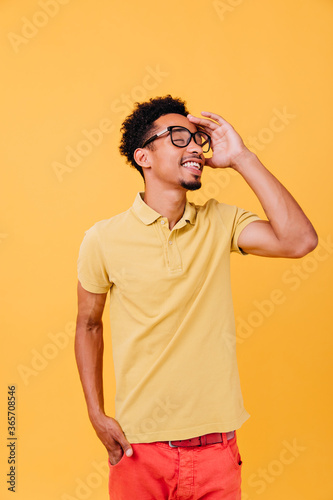 Smart guy in casual outfit posing with eyes closed. Indoor photo of pleasant african young man in glasses.