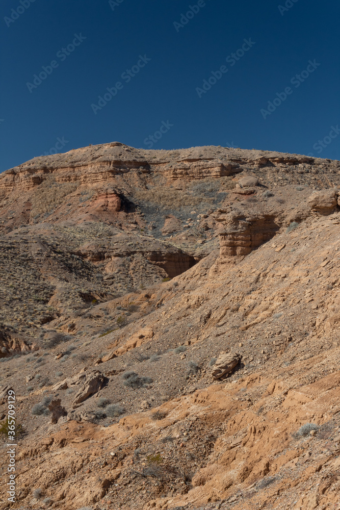 Deep blue sky above a series of inclines in the New Mexico desert, travel in the USA, creative copy space, vertical aspect