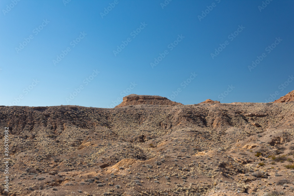 View across a wide valley in the New Mexico desert, vast open canyon with sage brush with blue sky, horizontal aspect