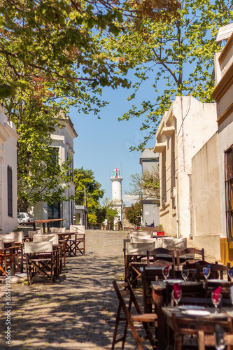 Obraz na płótnie A beautiful street with empty tables and restaurants in the city of Colonia del Sacramento, a cozy city in Uruguay, close to the River Plate, with tourist sites, such as a lighthouse and museums