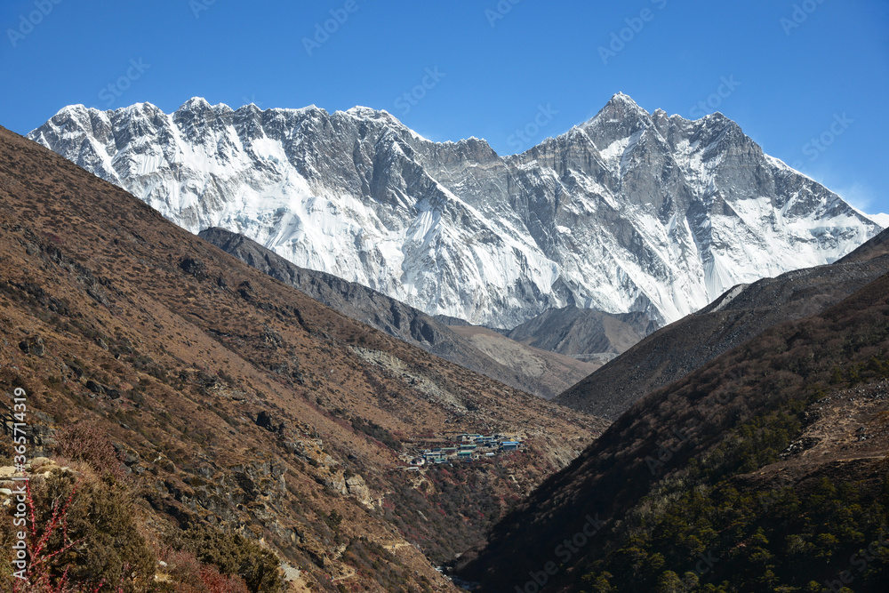 The enormous wall between Nuptse and Lhotse dwarfs the village of Shomare. The enormous wall between Nuptse and Lhotse dwarfs the village of Shomare.