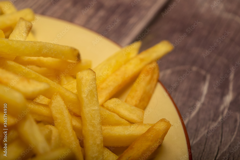 French fries in a round plate on a homespun cloth with a rough texture. Close up. French fries in a round plate on a homespun cloth with a rough texture. Close up.
