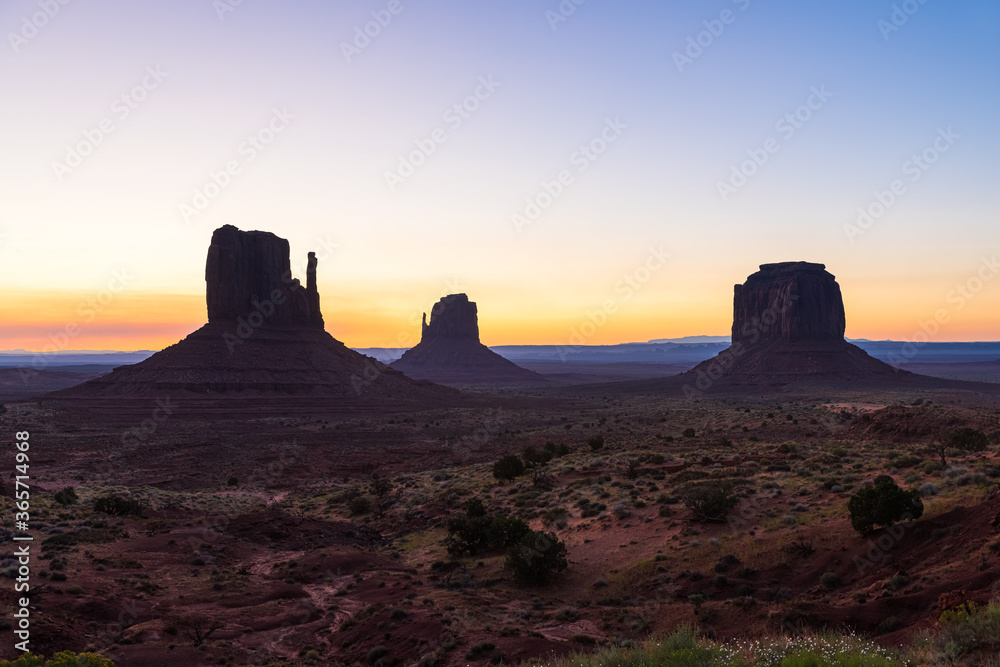 Monument Valley buttes silhouette and horizon view at dark dawn night with sunrise colorful light in Arizona in sky