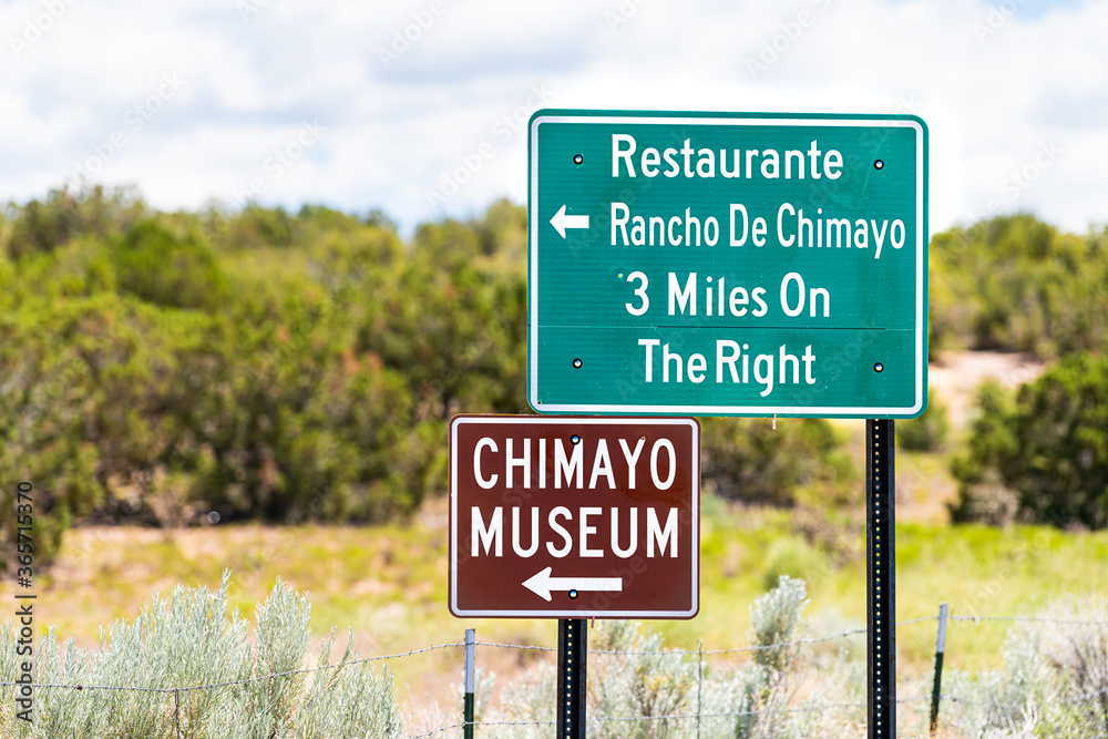 Scenic drive during summer at High Road to Taos famous trip near Santa Fe with direction signs for Chimayo town village museum and restaurants in New Mexico