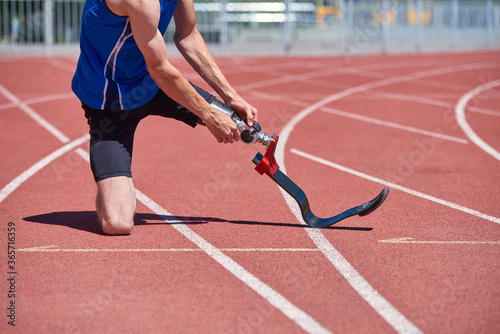 Sportsman fixing prosthetic foot at the start of running track