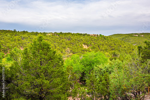 Sunset evening landscape on cloudy overcast day in Santa Fe, New Mexico mountains in community neighborhood with green plants pinon pine trees and adobe traditional houses photo