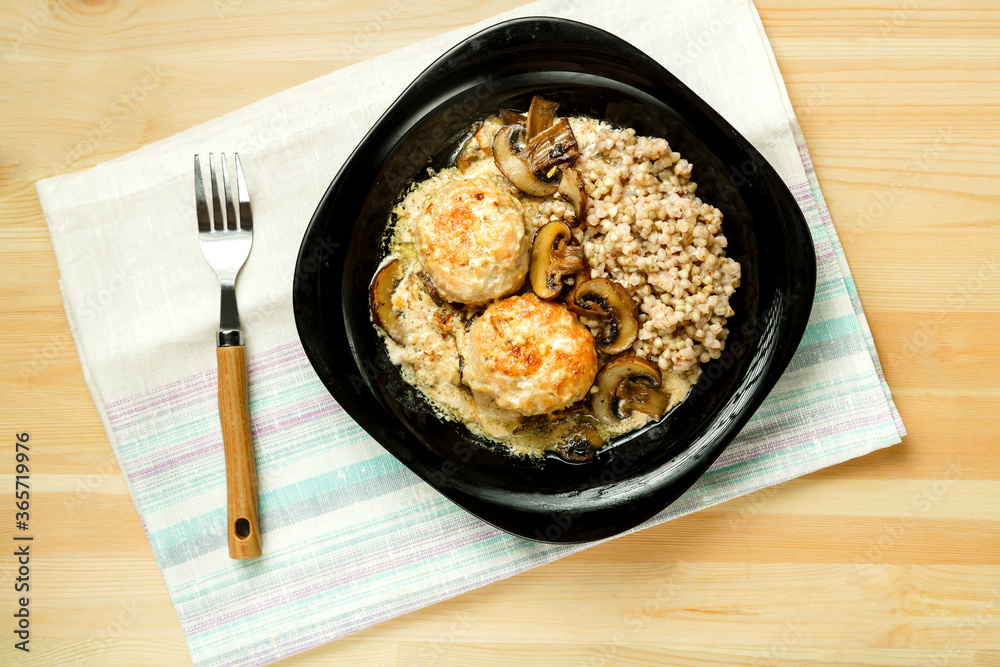 Chicken meatballs with mushrooms in a creamy sauce with green buckwheat in a plate on a linen napkin. Chicken meatballs with mushrooms in a creamy sauce with green buckwheat in a plate on a linen napkin.