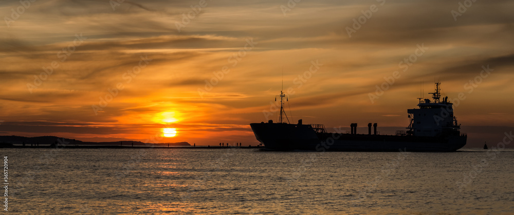 SUNSET BY THE SEA - An evening landscape by the sea coast and a ship going to the port
