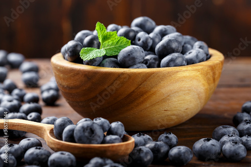Freshly picked blueberries in wooden bowl on a wooden  table. Healthy fruits.