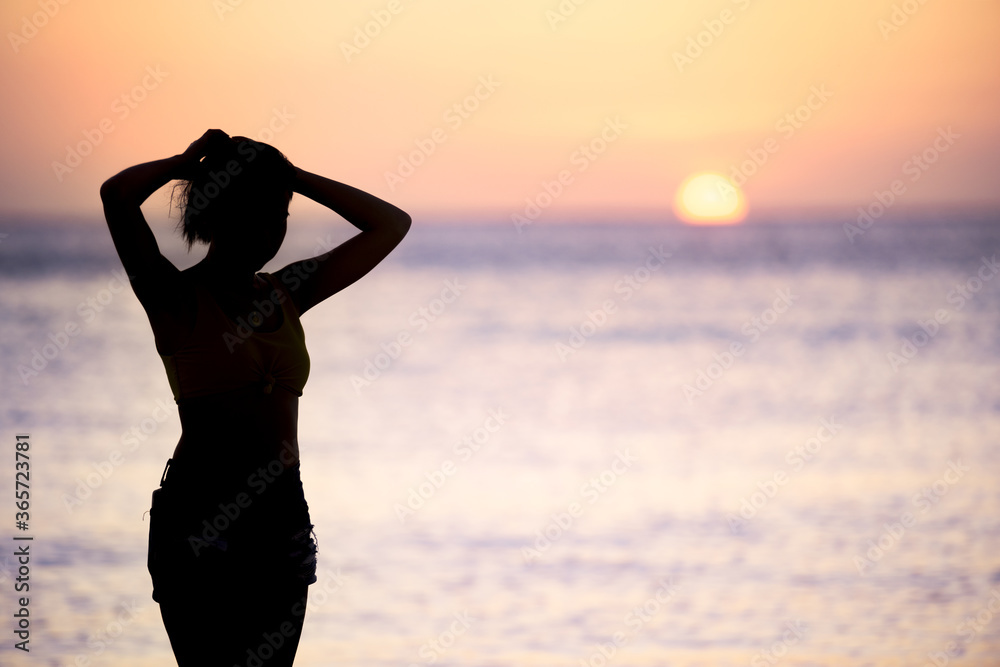 (Selective focus) Stunning view of the silhouette of a girl walking on a beach during a beautiful and romantic sunset. Siargao Island, Philippines.