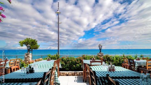 Typical interior of Cyprus restaurant with street flowers and view onto the blue sea