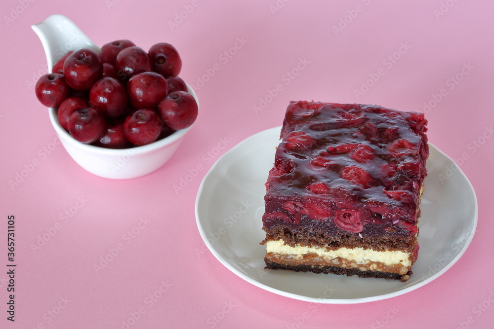 Cake with cherries and fresh cherries in white bowl close up on pink background Cake with cherries and fresh cherries in white bowl close up on pink background