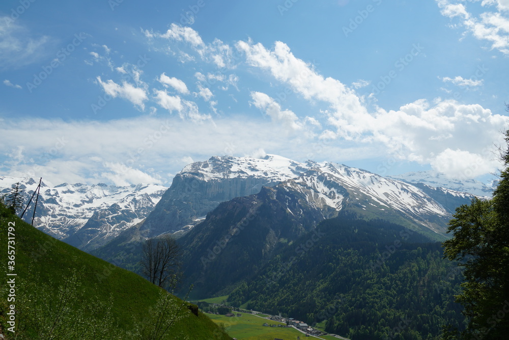 Obraz premium Landscape above village Engelberg in canton Obwalden in Switzerland in the springtime. The mountaintops and peaks are still covered with snow but in lower altitutes is everything green.