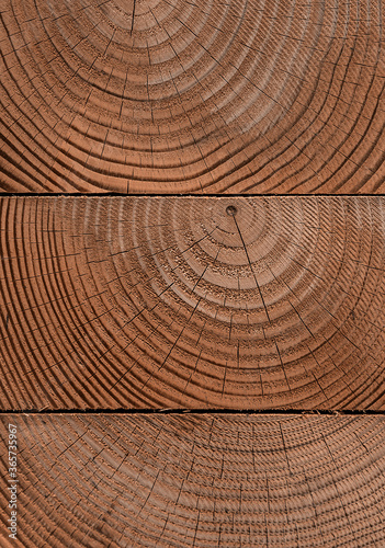 Stack of cleanly cut wooden beams shot straight on showing the woodgrain and tree rings.