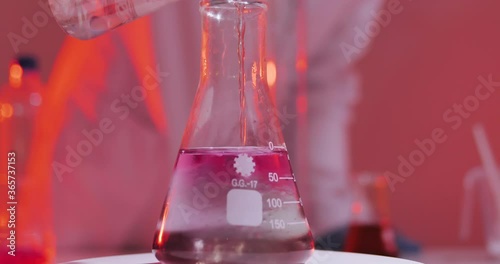 Laboratory worker scientist laboratory assistant tests chemicals for reactions in flask, interfering with different substances and obtaining a visual reaction. Concept of: Science, Chemistry.