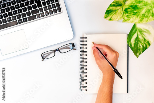 Businessman writing in notebook, small business office, freelance worker