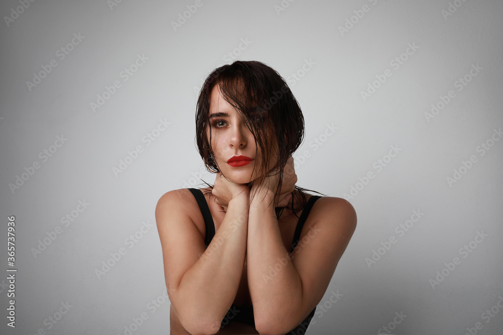 Beauty fashion portrait. Attractive young woman with wet hairstyle posing on grey wall background. Isolated. Beauty fashion portrait. Attractive young woman with wet hairstyle posing on grey wall background. Isolated.