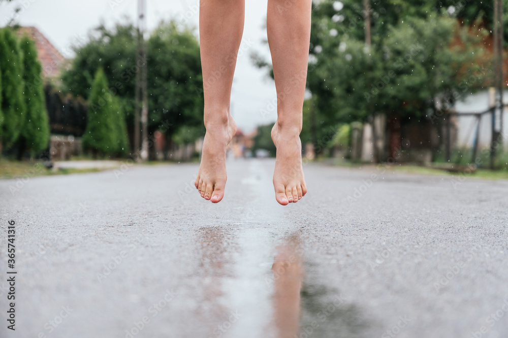 Feet of a woman jumping over a puddle in the rain Feet of a woman jumping over a puddle in the rain