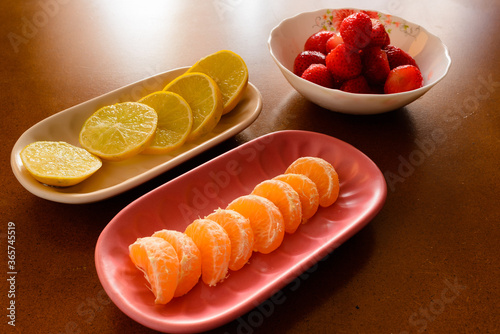 Fruits in bowls and plates over a wooden talbe, natural and backlighted
