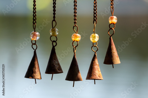 Wind chimes on chains hang off of a bird feeder