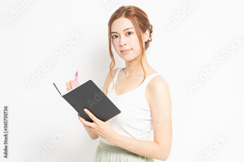 手帳にメモを書く若い女性