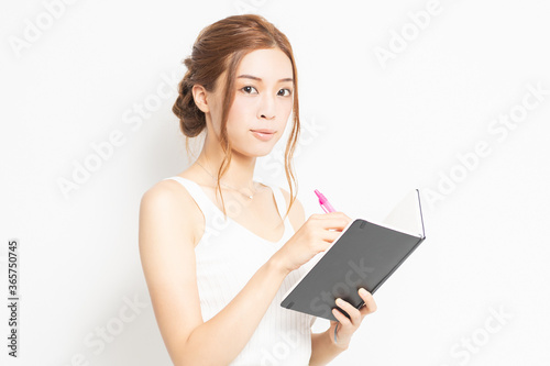 手帳にメモを書く若い女性