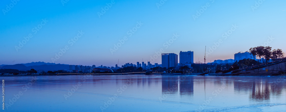 Frozen lake and skyline at blue hour