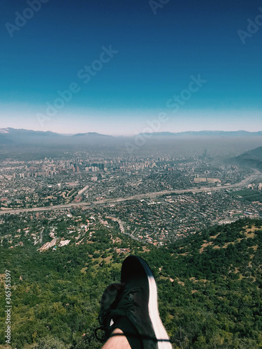 Guy sneakers and feet, and the amazing view of Santiago with pollution from the top of the Manquehuito hill (Chile) photo