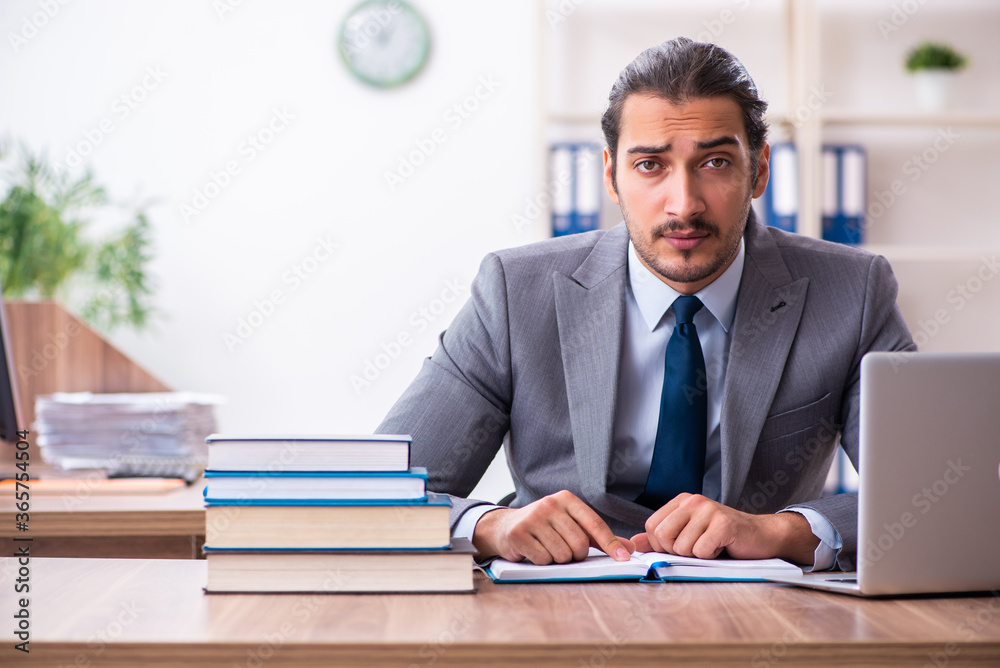 Young male businessman reading books at workplace Young male businessman reading books at workplace