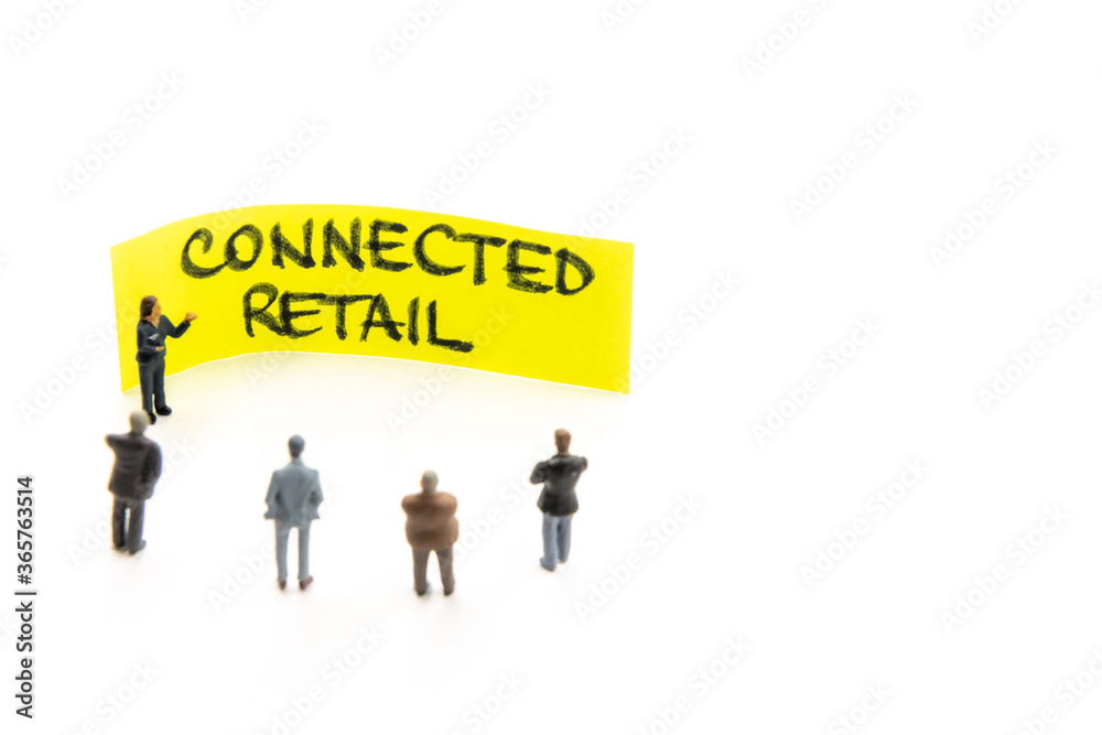 Meeting with miniature figurines posed as business people standing around post-it note with Connected Retail handwritten message in background, minimalist abstract concept with focus on text Meeting with miniature figurines posed as business people standing around post-it note with Connected Retail handwritten message in background, minimalist abstract concept with focus on text