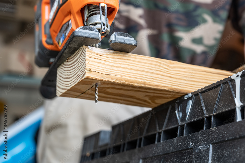 Underneath view as a jig saw cuts through a 2 x 4 pine board Underneath view as a jig saw cuts through a 2 x 4 pine board